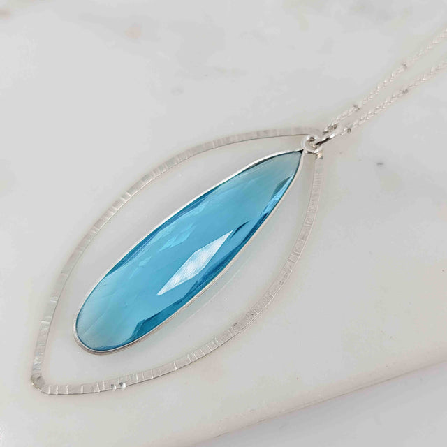 Teardrop Shaped Blue Topaz Surrounded by Textured Flat Wire Open Petal Necklace