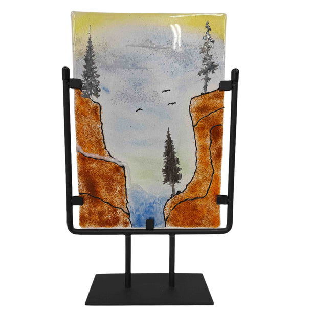 Decorative piece with cliffs and trees on a stand against a white background