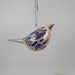 White and blue decorative glass bird with gold accents on a white background