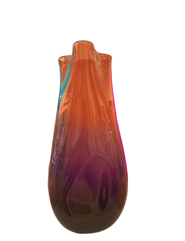 Gradient purple to orange vase on a white pedestal in an art gallery setting.